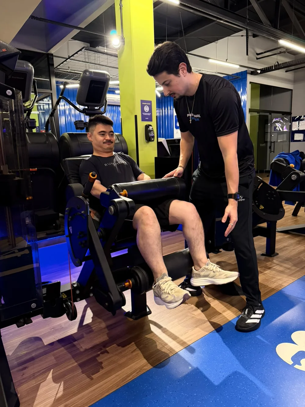 Vitor acompanhando um aluno durante exercício na máquina