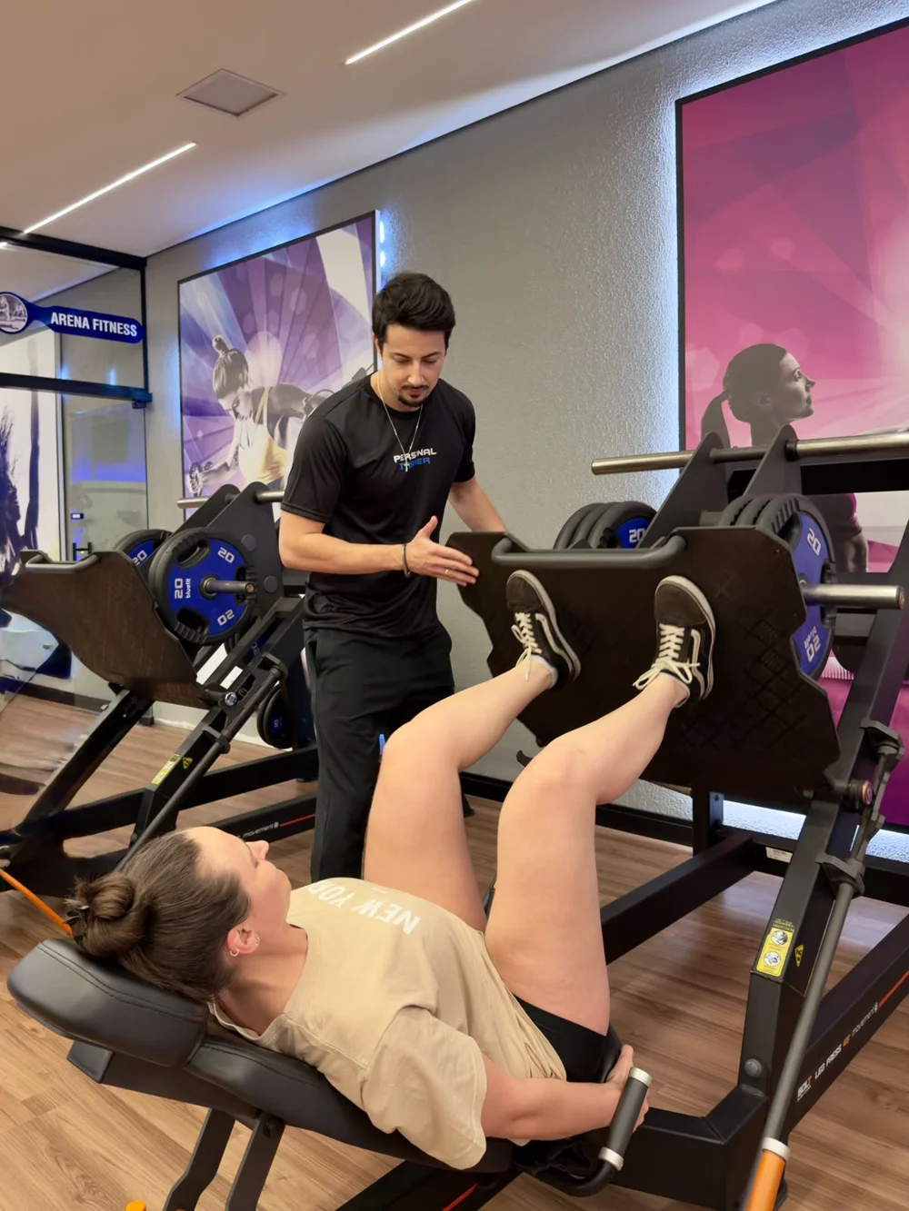 Vitor orientando uma aluna no leg press